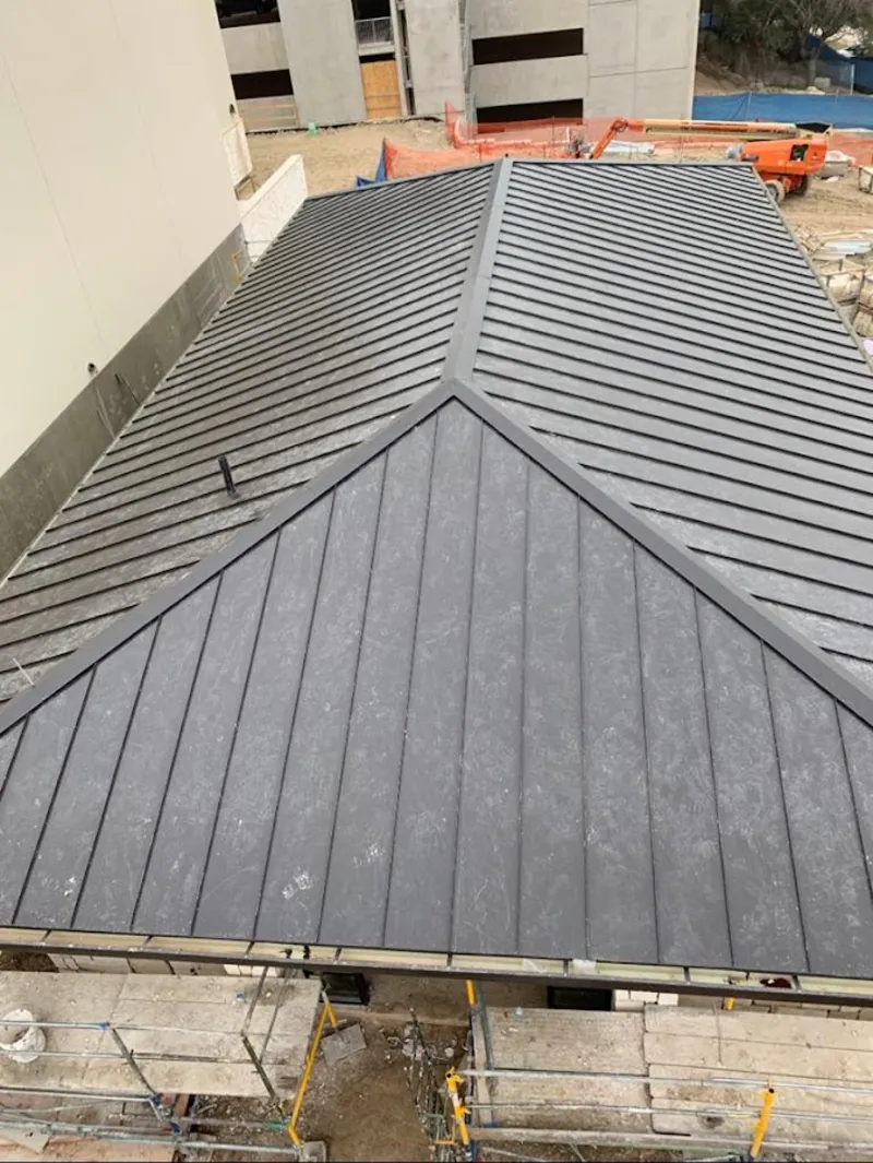 Commercial metal roof construction with crane equipment in Windham